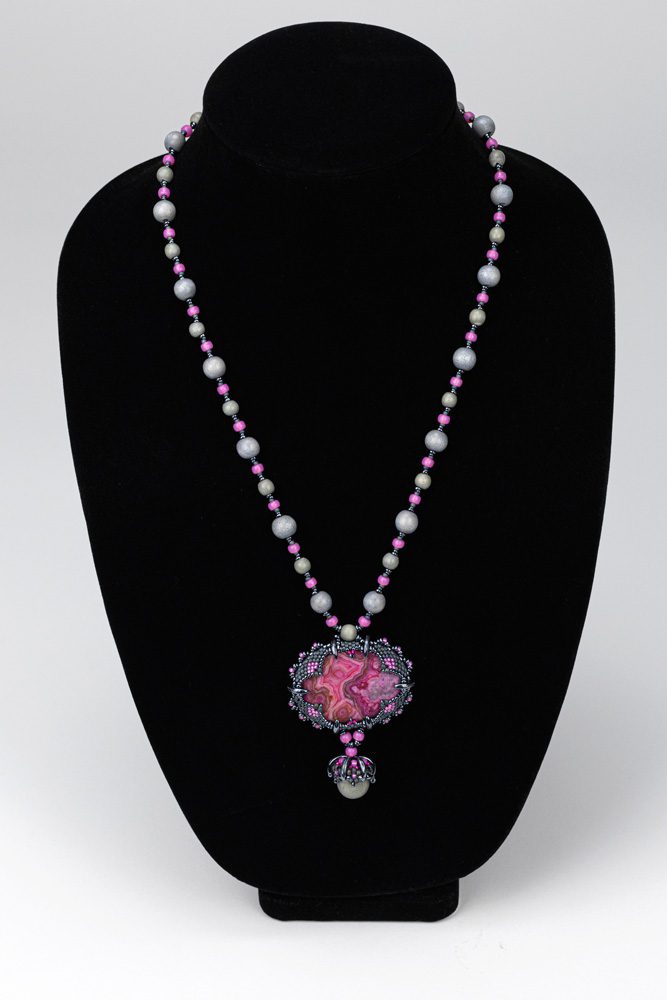 A black necklace with a pink and white bead necklace