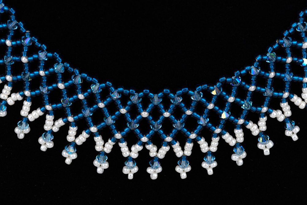 A blue and white necklace is shown on a black background.