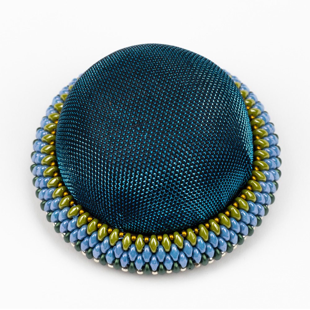 A blue and yellow brooch is shown on a white background.