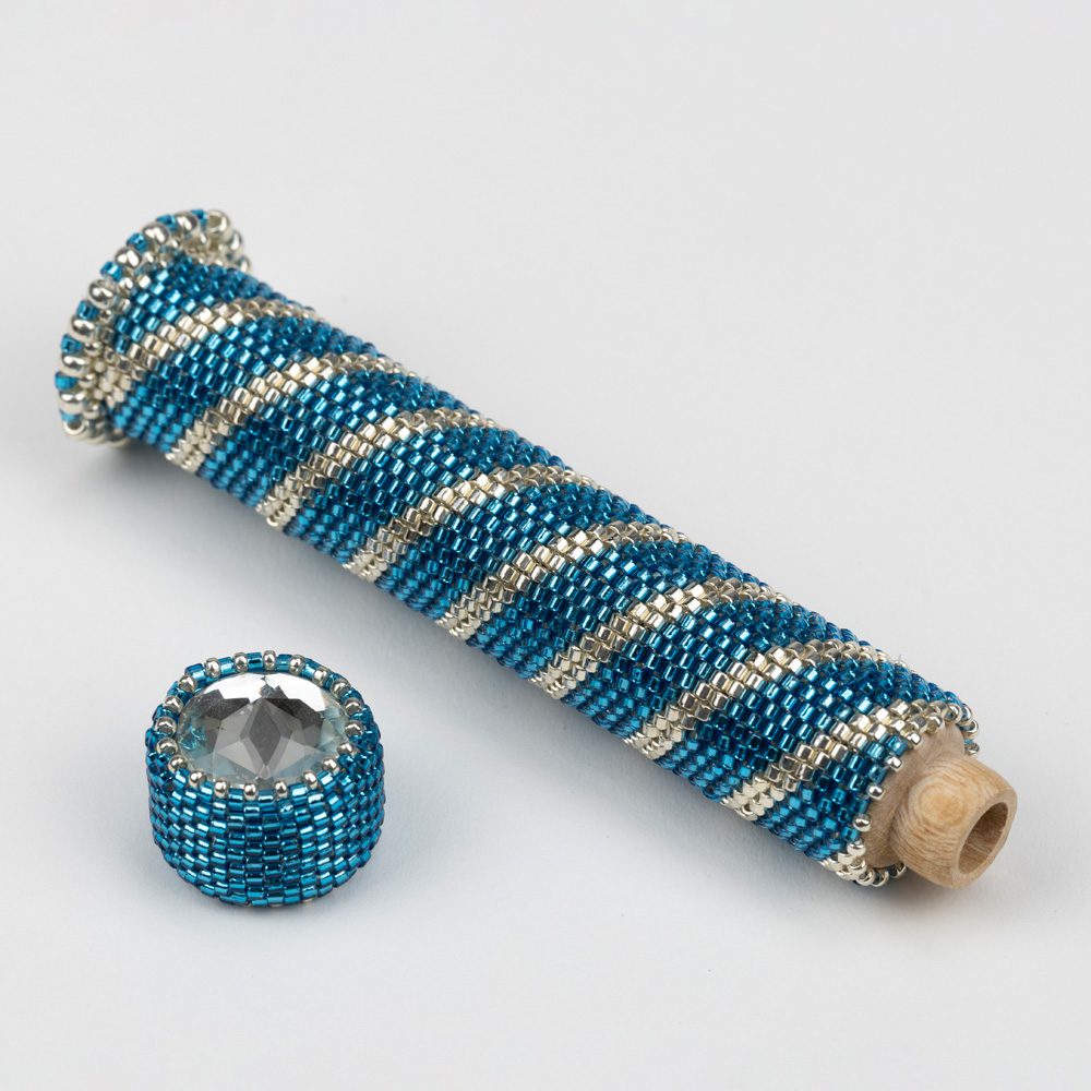 A blue and silver bead crochet tube with a ring.