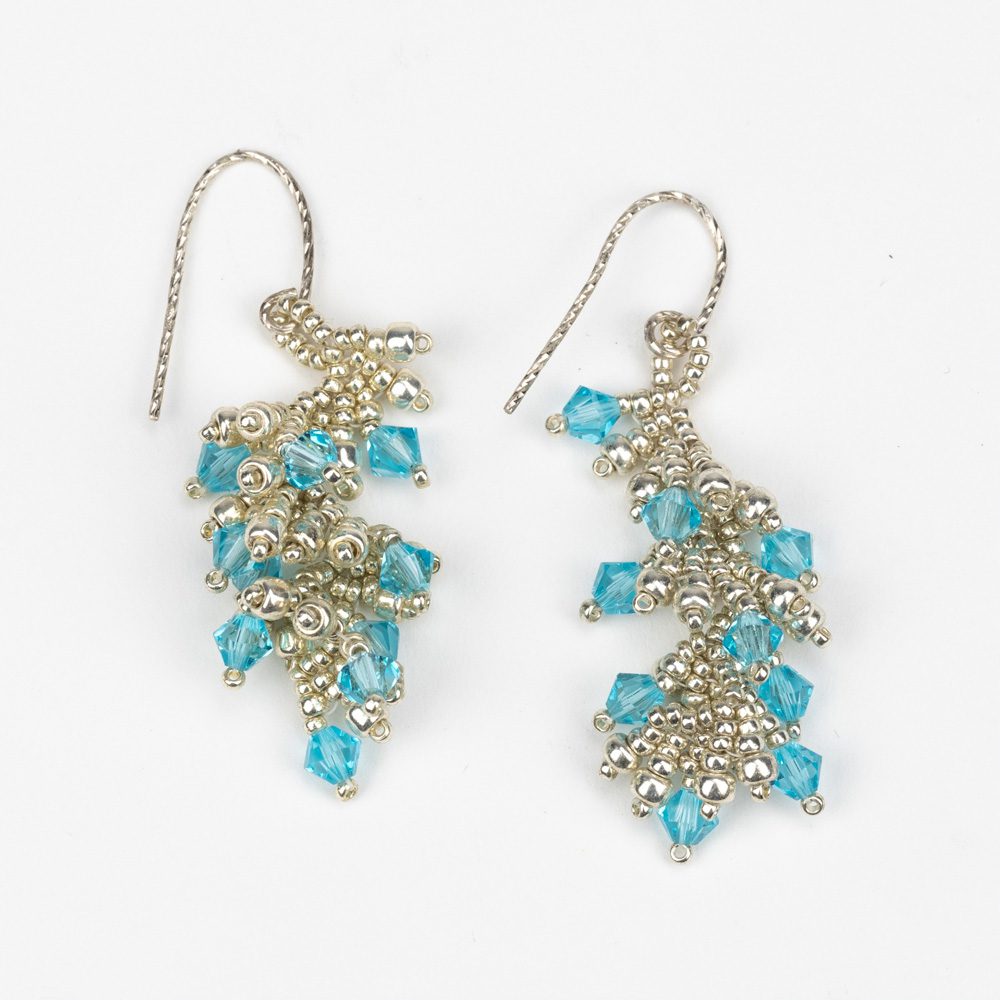 A pair of earrings with blue beads and silver chains.