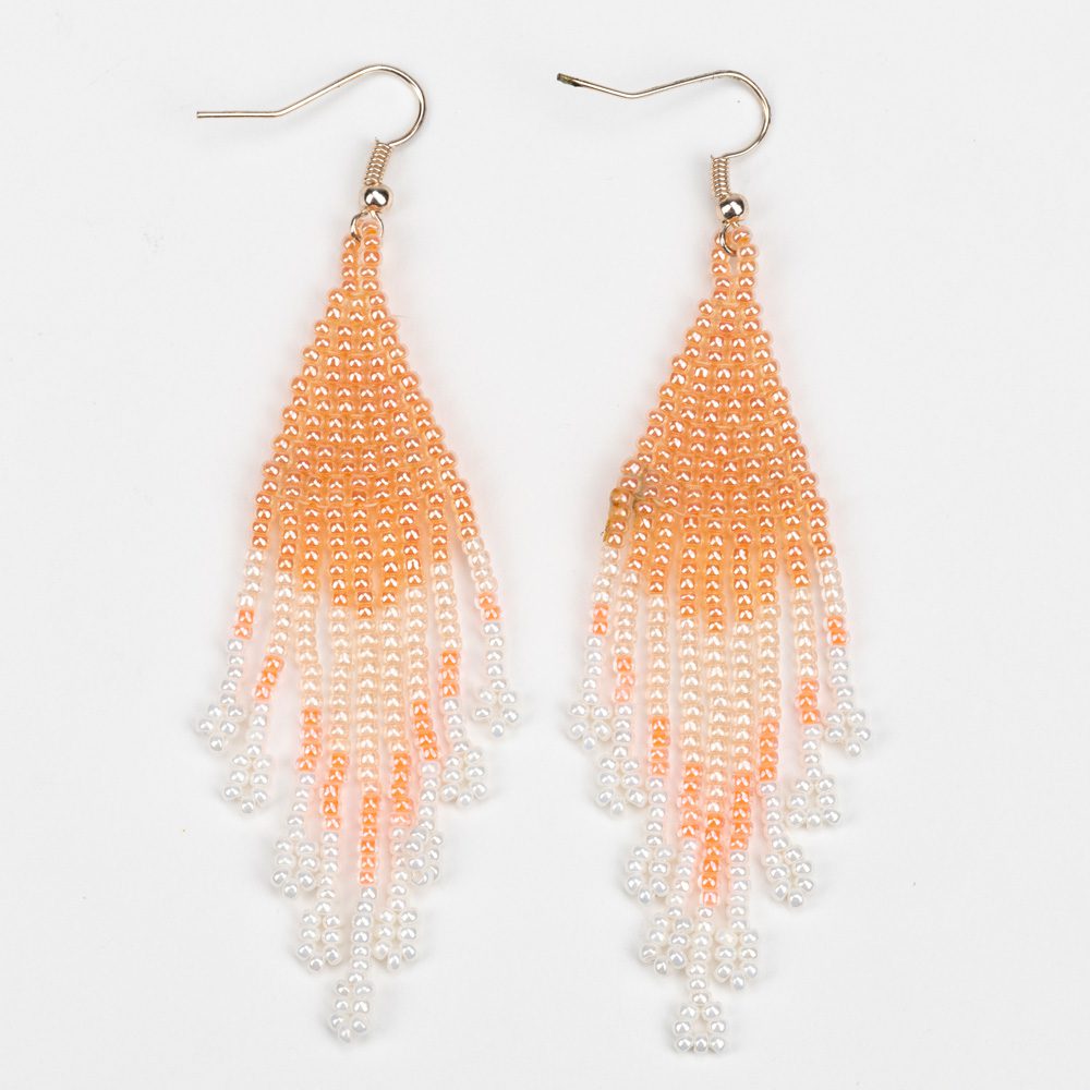 A pair of earrings with orange and white beads.