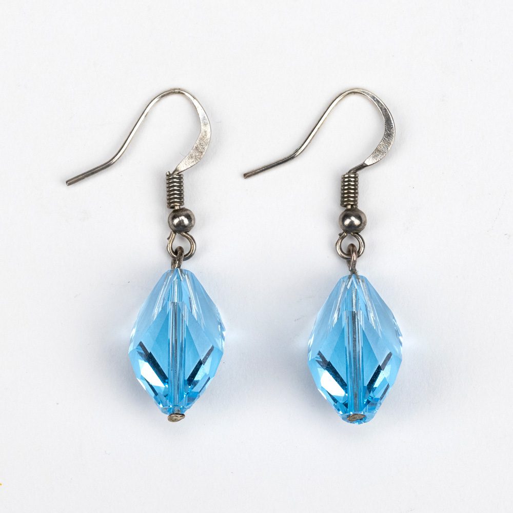 A pair of blue earrings hanging from silver hooks.