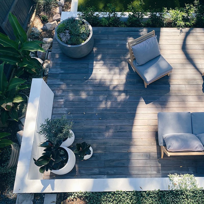 A patio with furniture and plants on top of it.